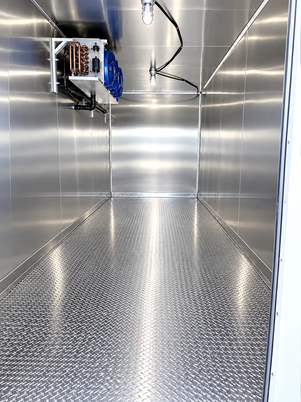 Stainless steel interior of a refrigerated trailer with cooling equipment and overhead lighting